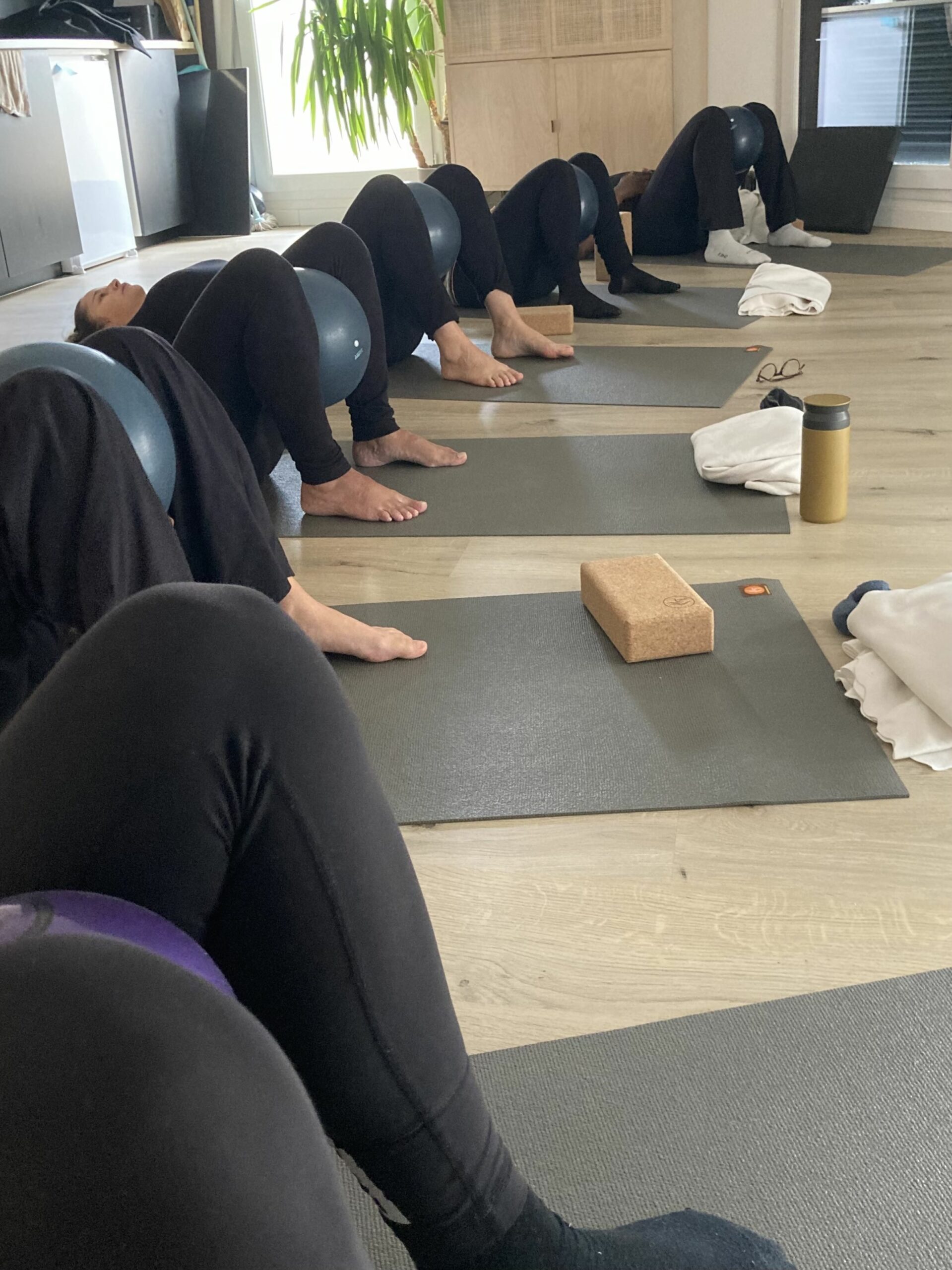 bienfaits-yoga-prénatal plusieurs femmes enceinte allongées en train de suivre unn cours de yoga prénatal